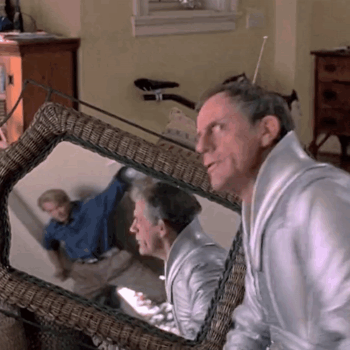 Man Looking At Reflection In Wicker Chair GIF