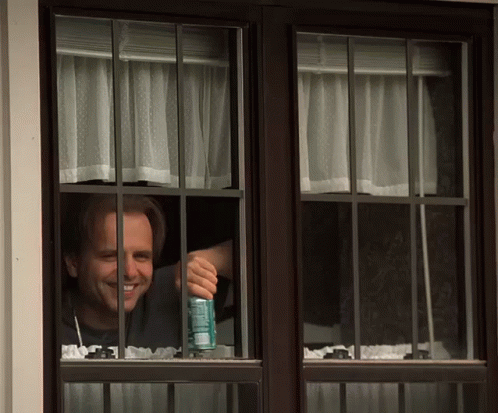 Man Looking Out Window Holding a Soda