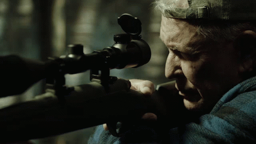 Man Looking Through Sniper Scope With Hat on Head