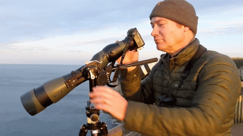 Man Looking Through Telescope With Camera