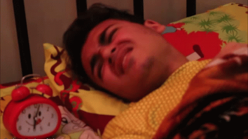 Man Lying in Bed Next to Red Alarm Clock