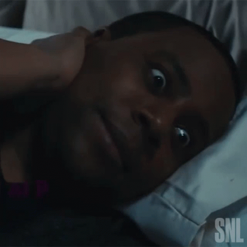 Man Lying in Bed With SNL Logo on Face