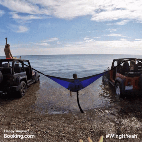 Man Lying in Hammock Between Two Jeep Wranglers on Beach