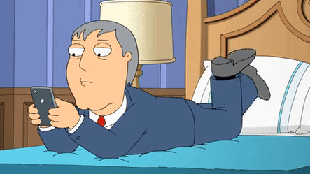 Man Lying on Bed Looking at Cell Phone