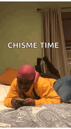 Man Lying on Bed Looking at Phone Chisme Time