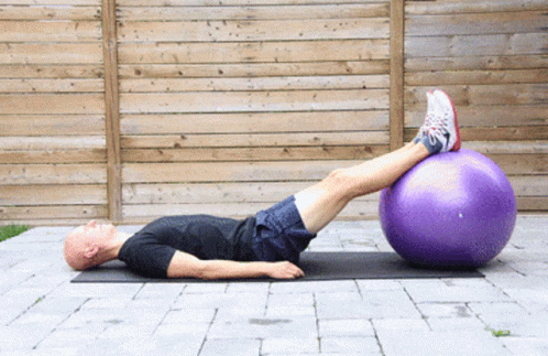 Man Lying on Mat With Legs on Purple Ball