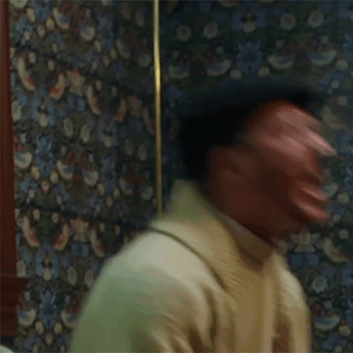 Man Making Funny Face in Front of Patterned Wallpaper