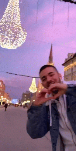 Man Making Heart With Hands in Front of Christmas Tree