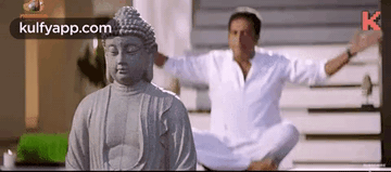 Man Meditating Before Buddha Statue