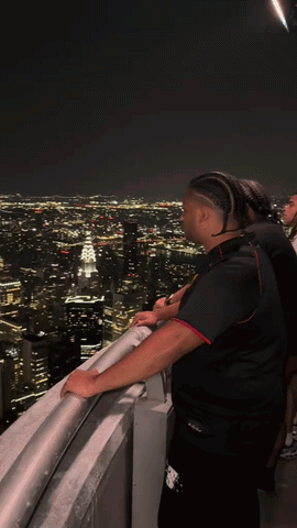Man on Balcony Overlooking City at Night