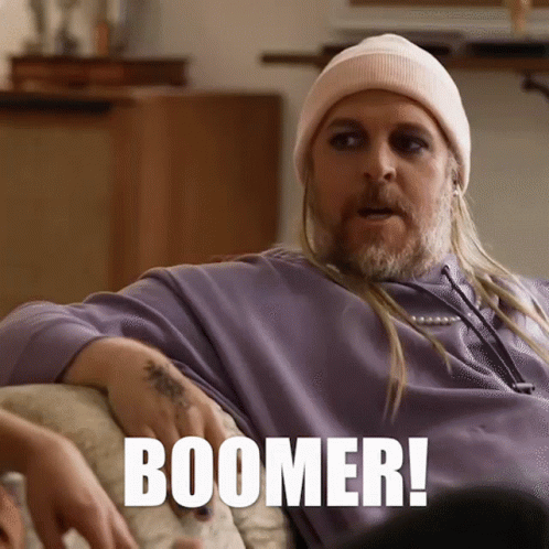Man on Couch With Long Hair and Beanie Says Boomer