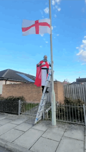 Man on Ladder Holding Red and White Cross Flag