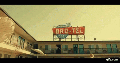 Man on Motel Balcony With Bro-Tel Vacancy Sign
