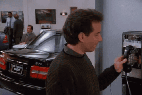 Man on Pay Phone Next to Car Saying Night