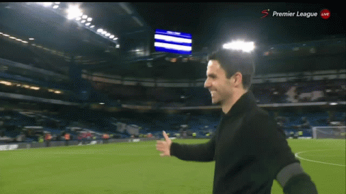 Man on Soccer Field With Premier League Screen