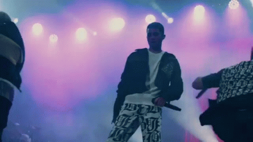 Man On Stage Holding Microphone With Dancers GIF