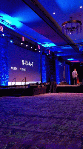 Man on Stage in Front of NBA T Need Budget Screen