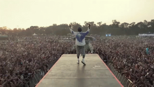 Man on Stage With Arms Outstretched Before Crowd