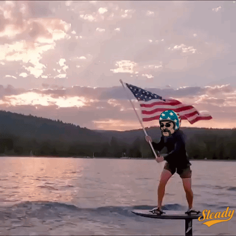 Man On Surfboard Holding American Flag GIF