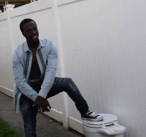Man on Toilet Beside Fence