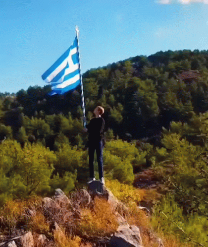 Man On Top Of Mountain Lifting Greece Flag GIF