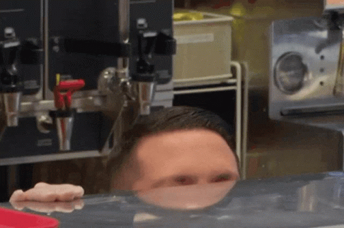 Man Peeking Over Counter With Reflection GIF