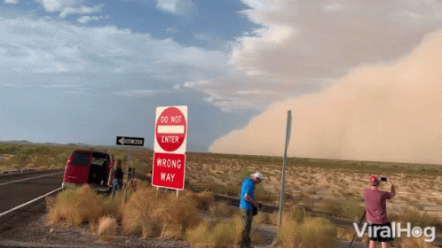 Man Photographing Do Not Enter And Wrong Way Signs GIF