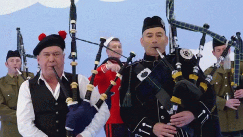 Man Playing Bagpipe with Scottish Badge
