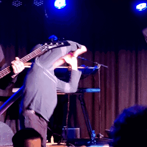 Man Playing Bass Guitar on Stage with Keyboard