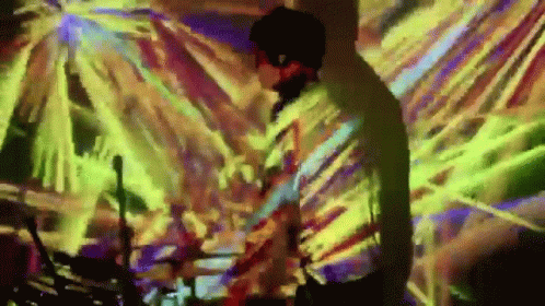 Man Playing Drums In Front Of Colorful Wall GIF