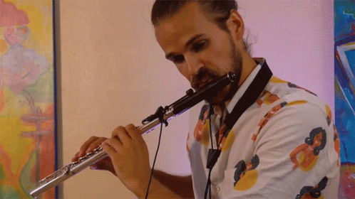 Man Playing Flute in Front of Colorful Painting