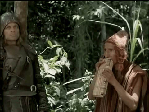 Man Playing Flute in Woods With Another Man