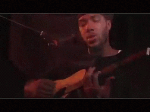 Man Playing Guitar and Singing Into Mic