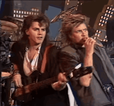 Man Playing Guitar and Singing Into Microphone With Drummer