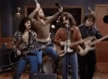Man Playing Guitar and Singing Into Microphone With Drummer