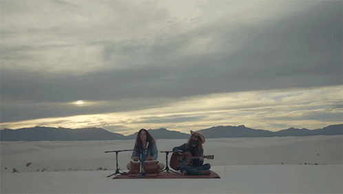 Man Playing Guitar and Woman Playing Drum in Desert
