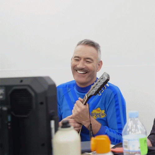 Man Playing Guitar in Blue Wiggles Shirt