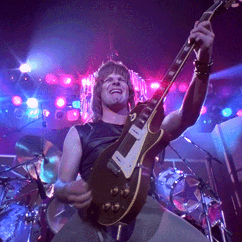 Man Playing Guitar in Dark Room With Purple Lights