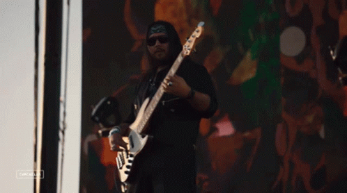 Man Playing Guitar in Front of Cacahua Screen