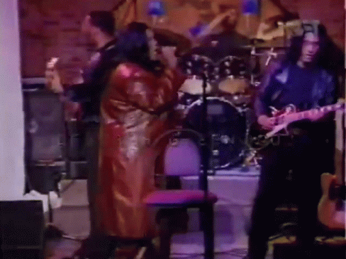 Man Playing Guitar in Front of Drum Set With Woman Singing