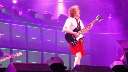 Man Playing Guitar in Front of Marshall Amps