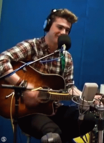 Man Playing Guitar in Front of Microphone
