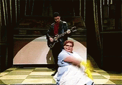 Man Playing Guitar Next to Dancing Woman