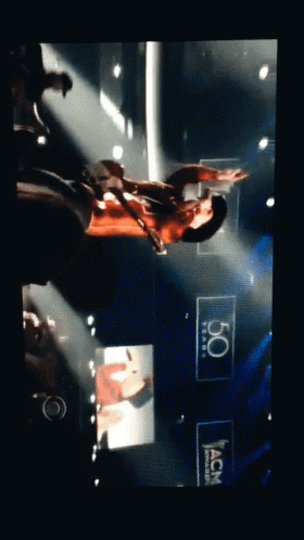 Man Playing Guitar on Stage With 50 Years ACM Sign