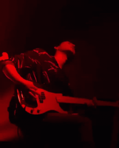 Man Playing Guitar with Headphones on Red Wall