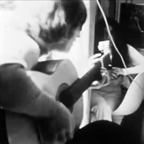 Man Playing Guitar with Woman Watching