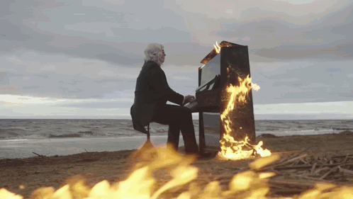 Man Playing Piano on Beach with Fire