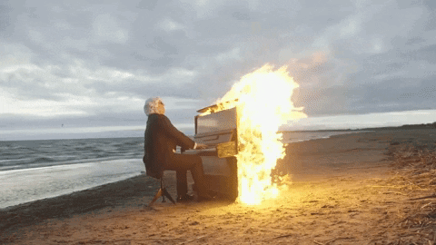 Man Playing Piano with Flames on Beach