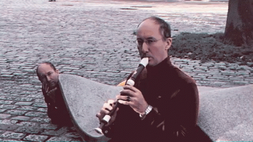 Man Playing Recorder on Stone Bench