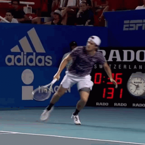 Man Playing Tennis in Front of Adidas Sign